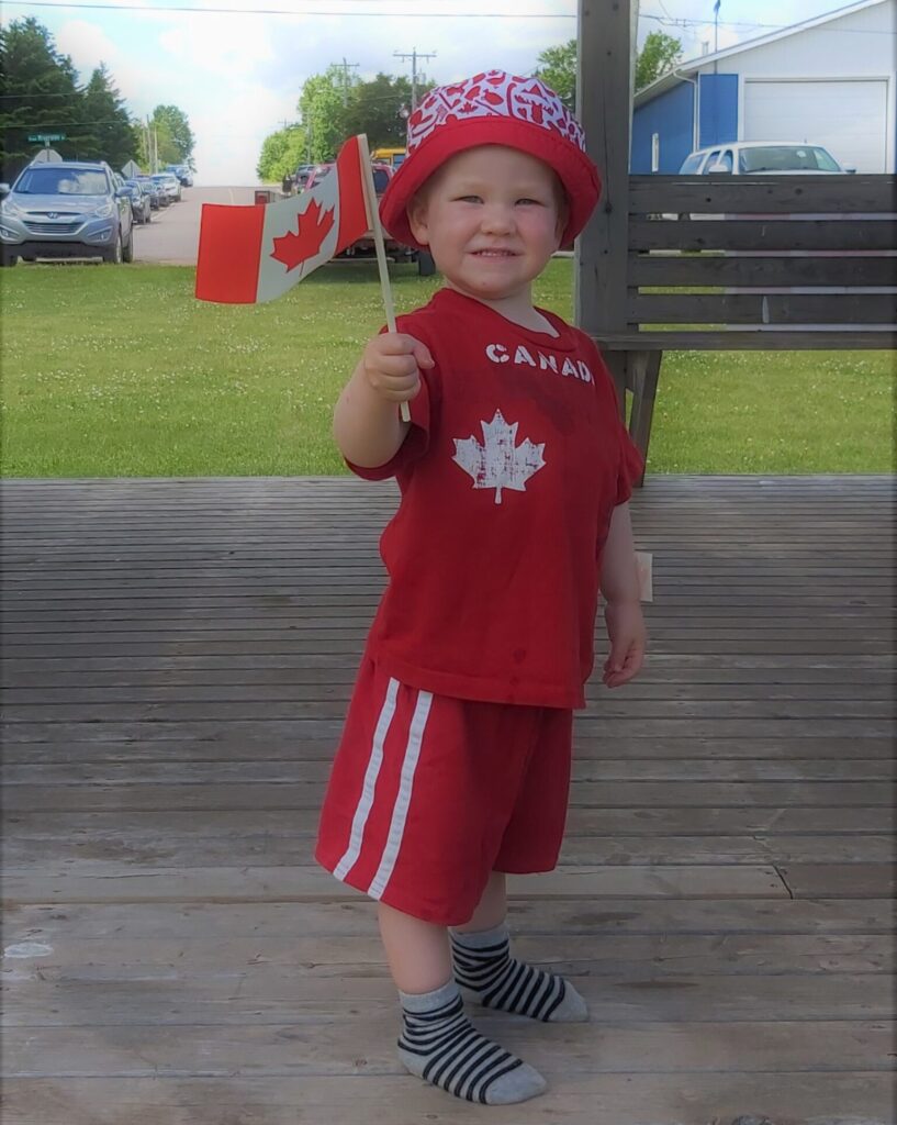 A child in Morell, dressed in red, waving his Canadian flag.